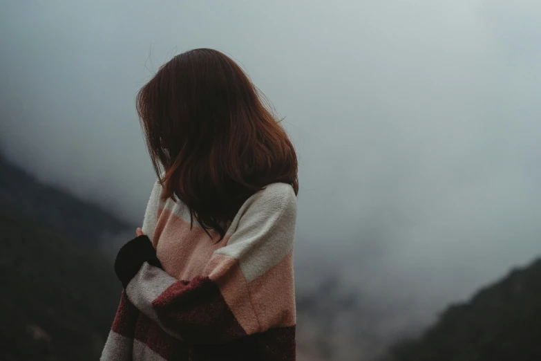 a woman in plaid sweater on a foggy mountain