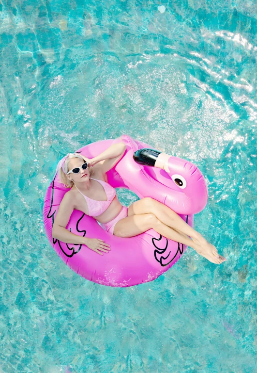 a woman floating in the pool on an inflatable pink flamingo