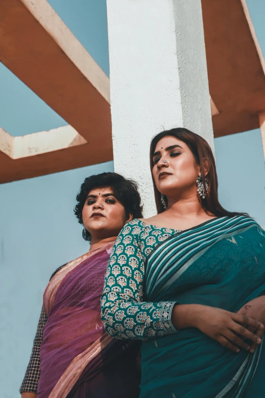 two beautiful women in colorful clothing hanging on a structure