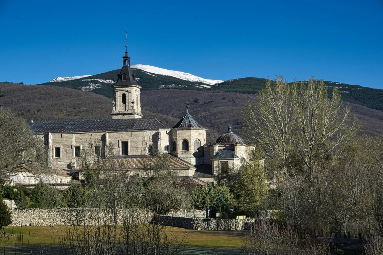 old stone building in front of mountains with trees