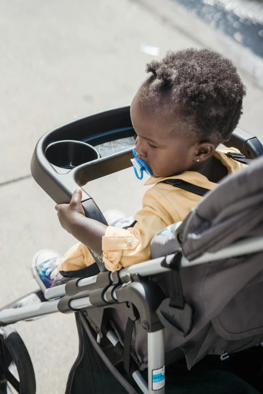 a small baby in a stroller looks at a cell phone