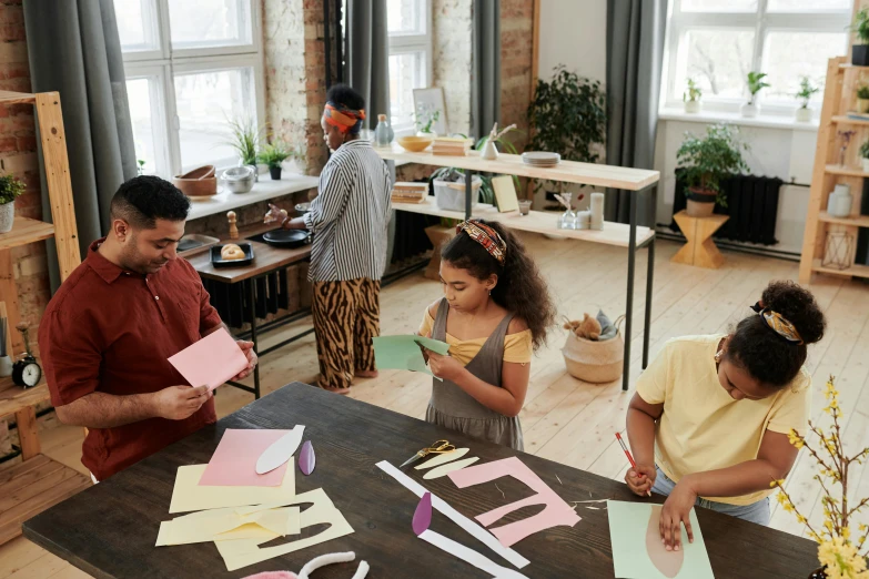 three people standing in a living room making crafts