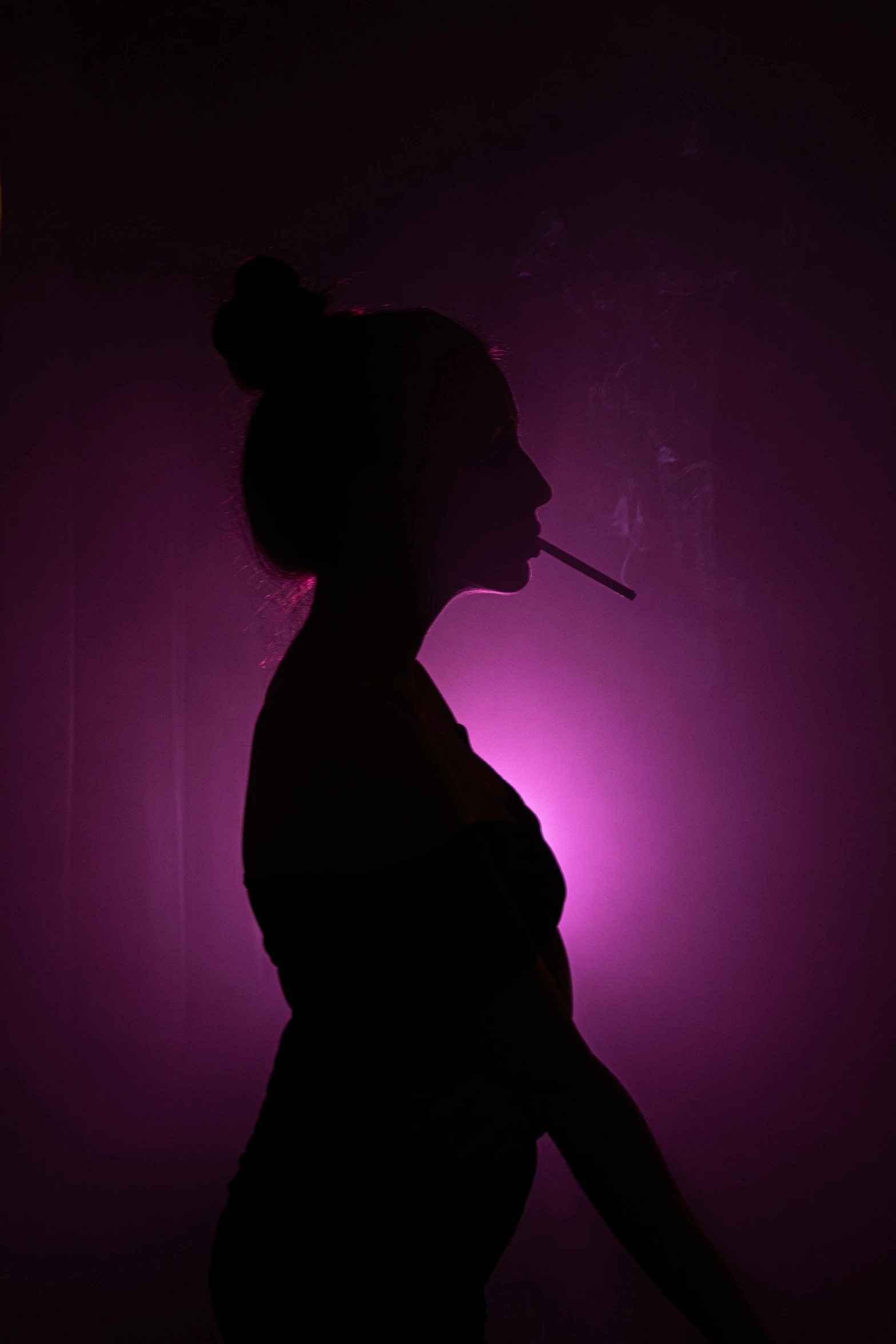 a woman smoking a cigarette in silhouette against a dark background