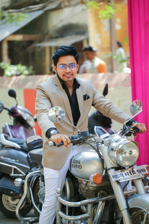 a man in a suit and glasses poses on a motorcycle