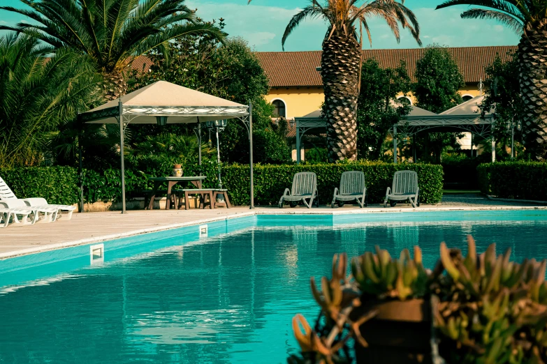 the pool is surrounded by lawn chairs and palm trees