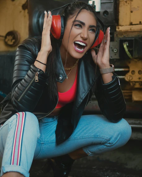 a young woman in a leather jacket and headphones with her hands together