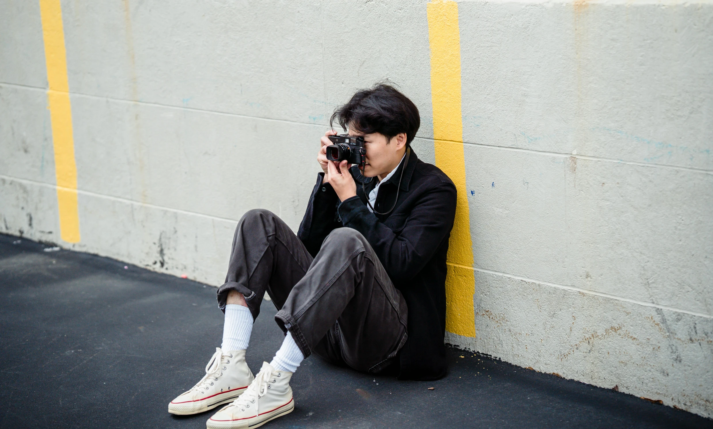 a young man is sitting on the ground holding a camera