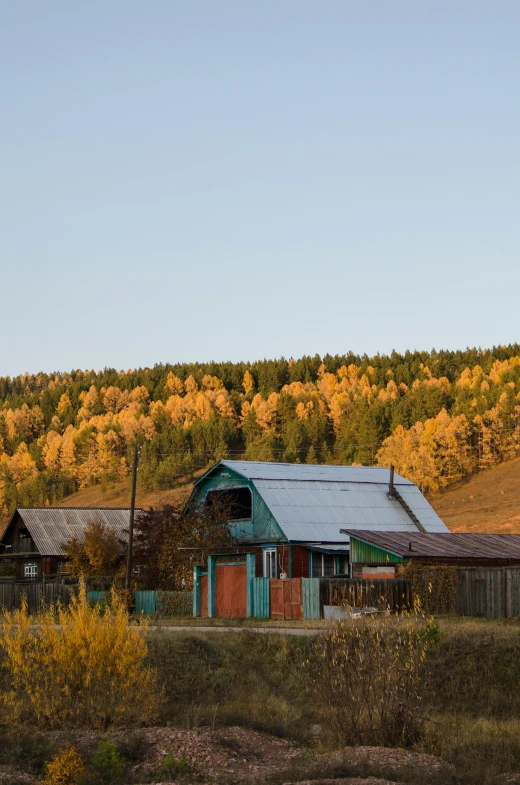 an old barn with fall colors behind it