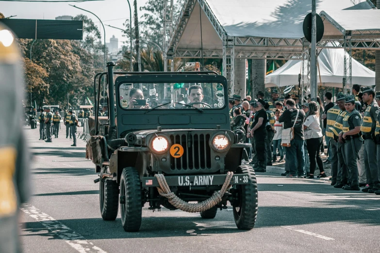 a jeep driving down a road with people in the background