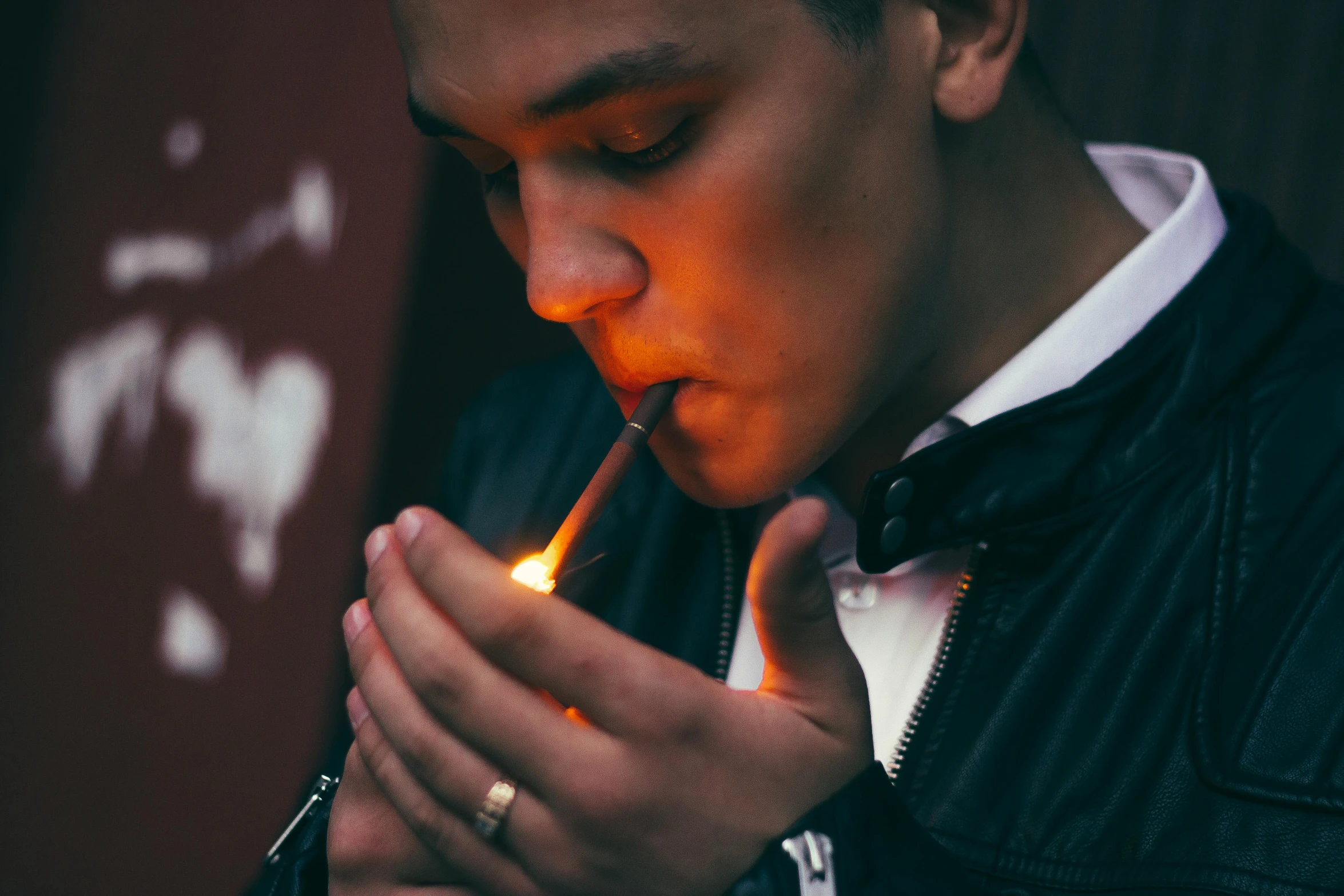 a young man lighting a match with an orange lighter