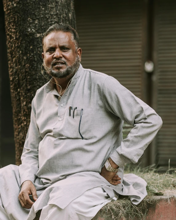 a man is sitting on a ledge beside a tree