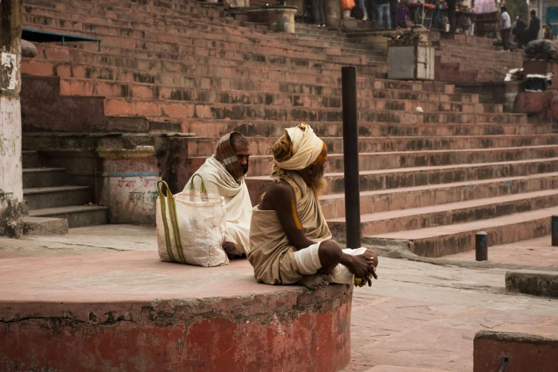 two people sitting on stone steps one wearing a hat and the other wearing a scarf