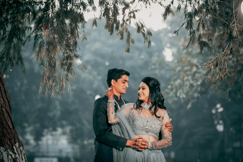 a beautiful young couple emcing under a tree