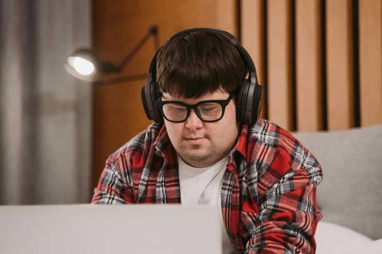 the man is wearing headphones and working on his laptop