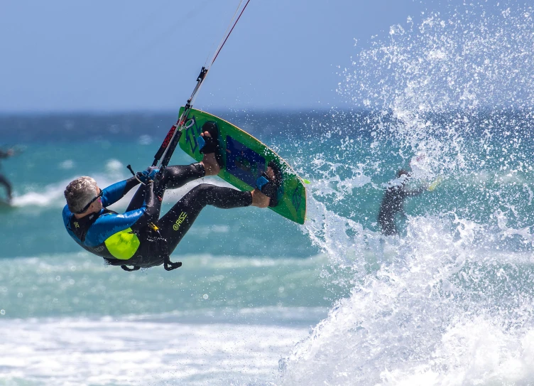 a person doing tricks in the ocean while holding on to a kite