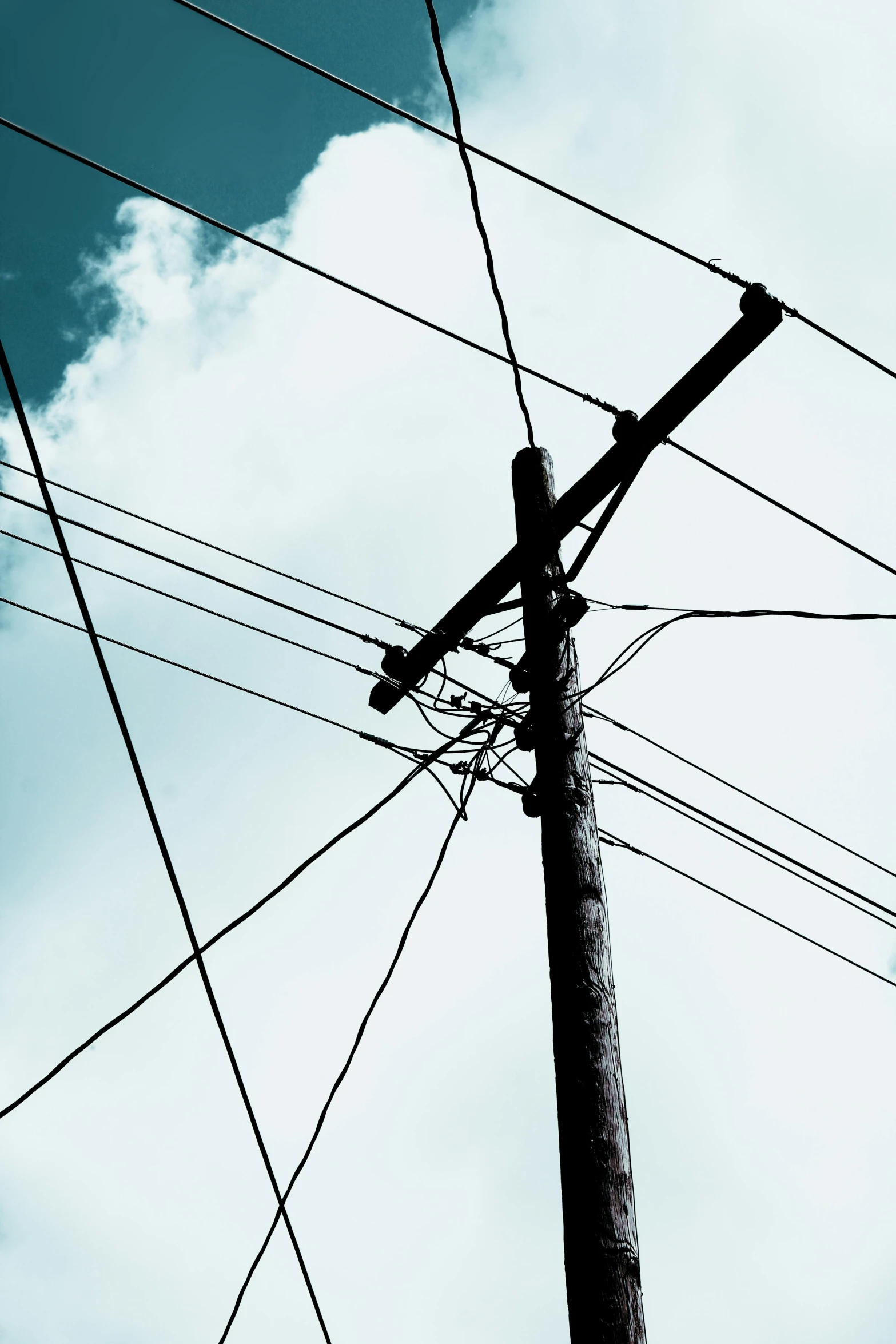 a pole is holding electrical wires under the cloudy sky