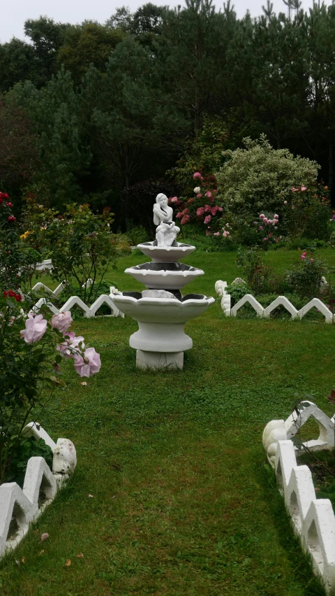 a garden has a fountain surrounded by ornamental flowers