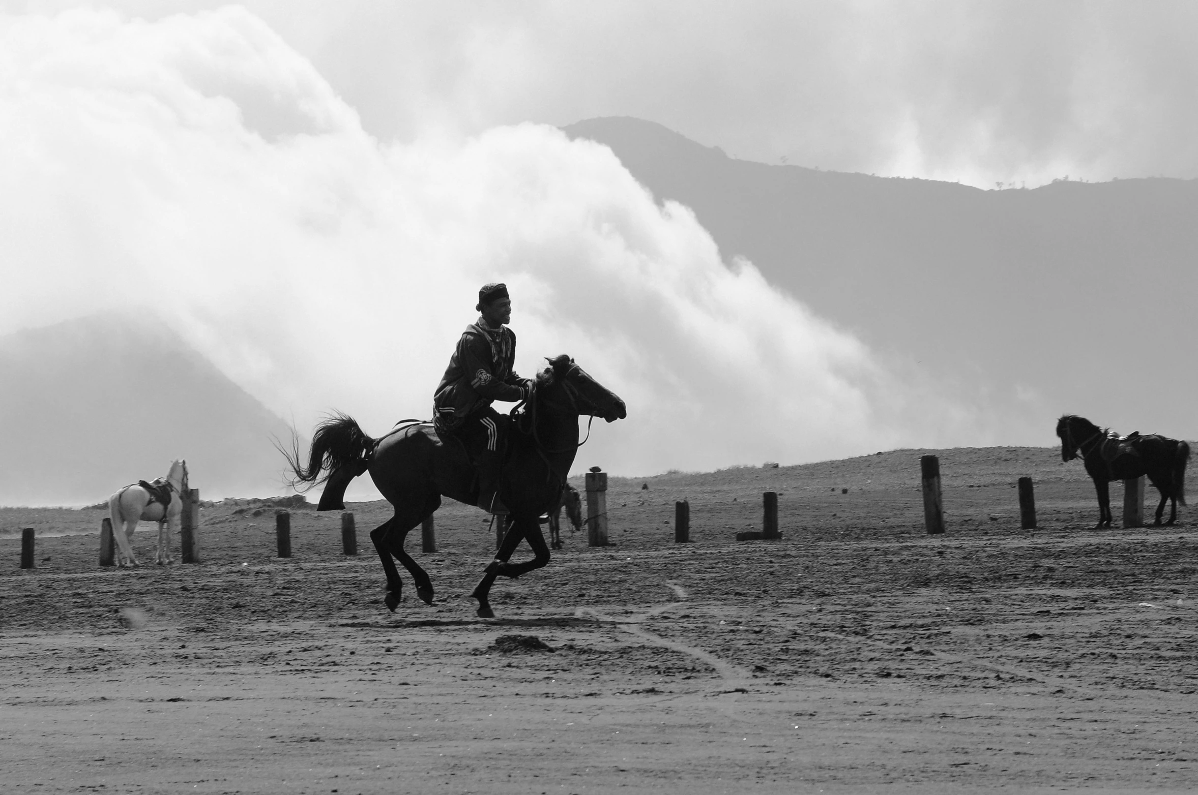 black and white image of people on horseback in open field