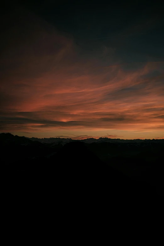 the sunset view of a plane flying over the mountains