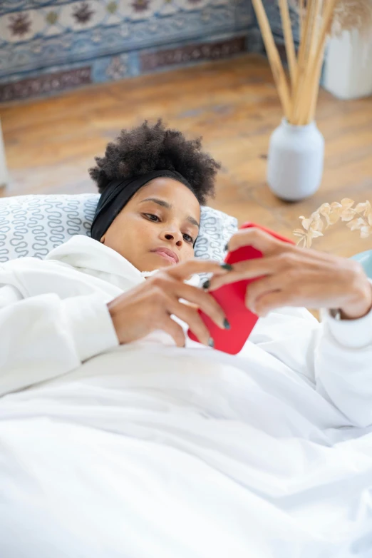 a woman with headphones in bed and using a red phone