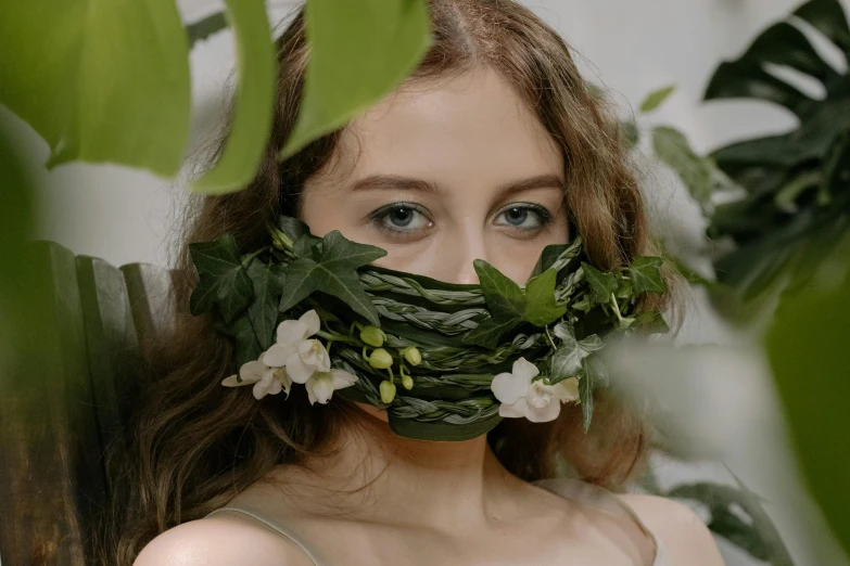 the woman is hiding behind leaves and looking at the camera