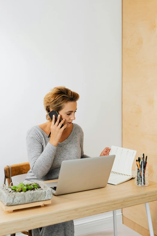 a woman sitting at her desk on a cell phone