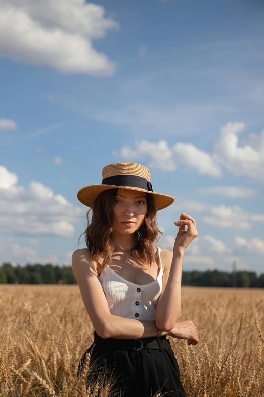 woman in wide brimmed hat standing in a wheat field