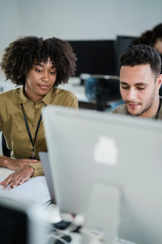 two people sitting at a table with computers