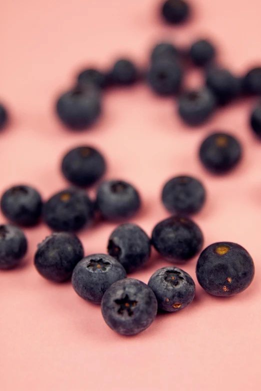 blueberries scattered around on a pink surface