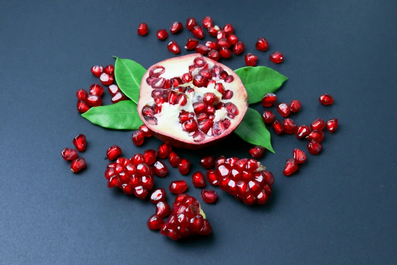 a pomegranate with leaves sitting on a blue surface