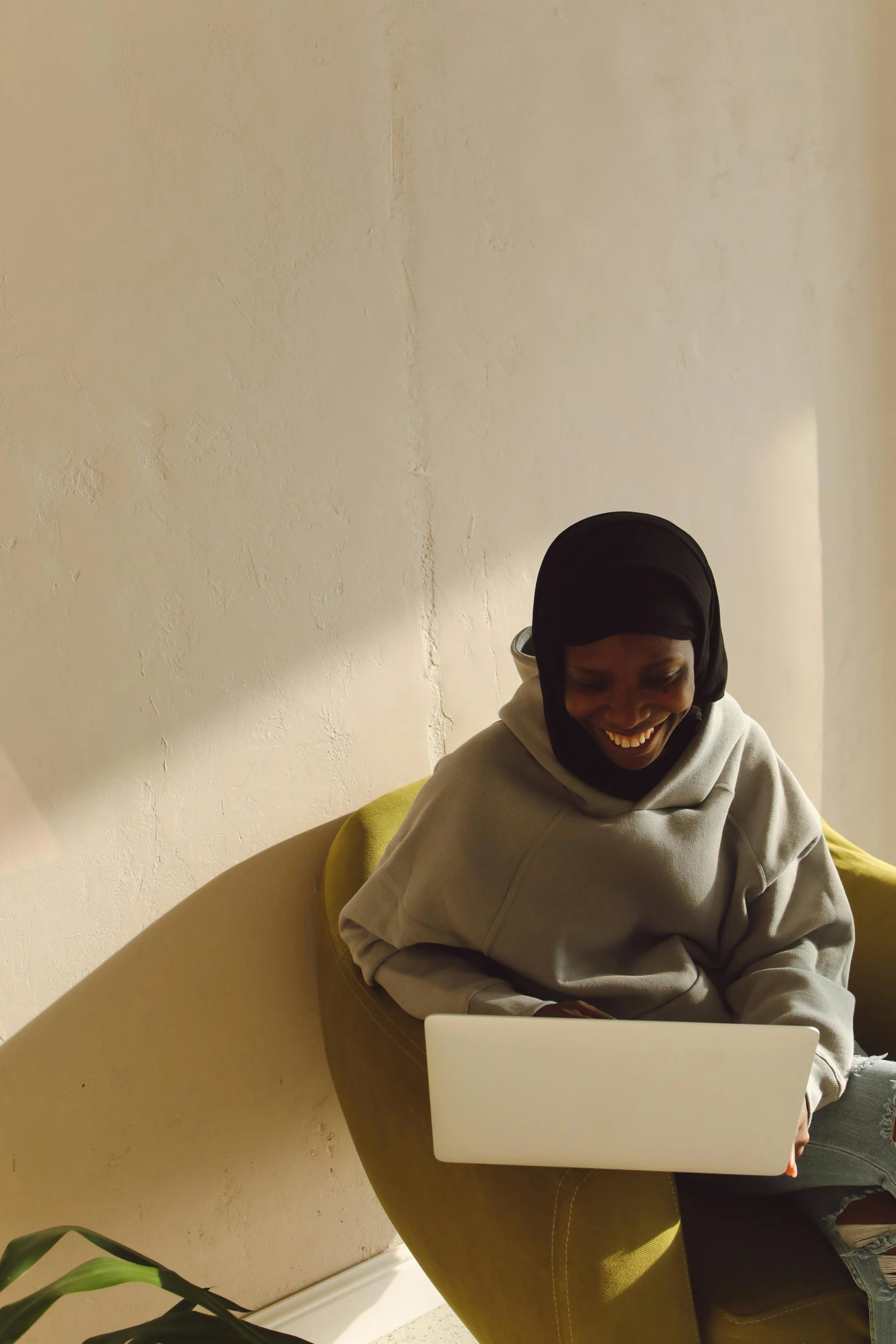 a person in grey jacket sitting on a chair with laptop