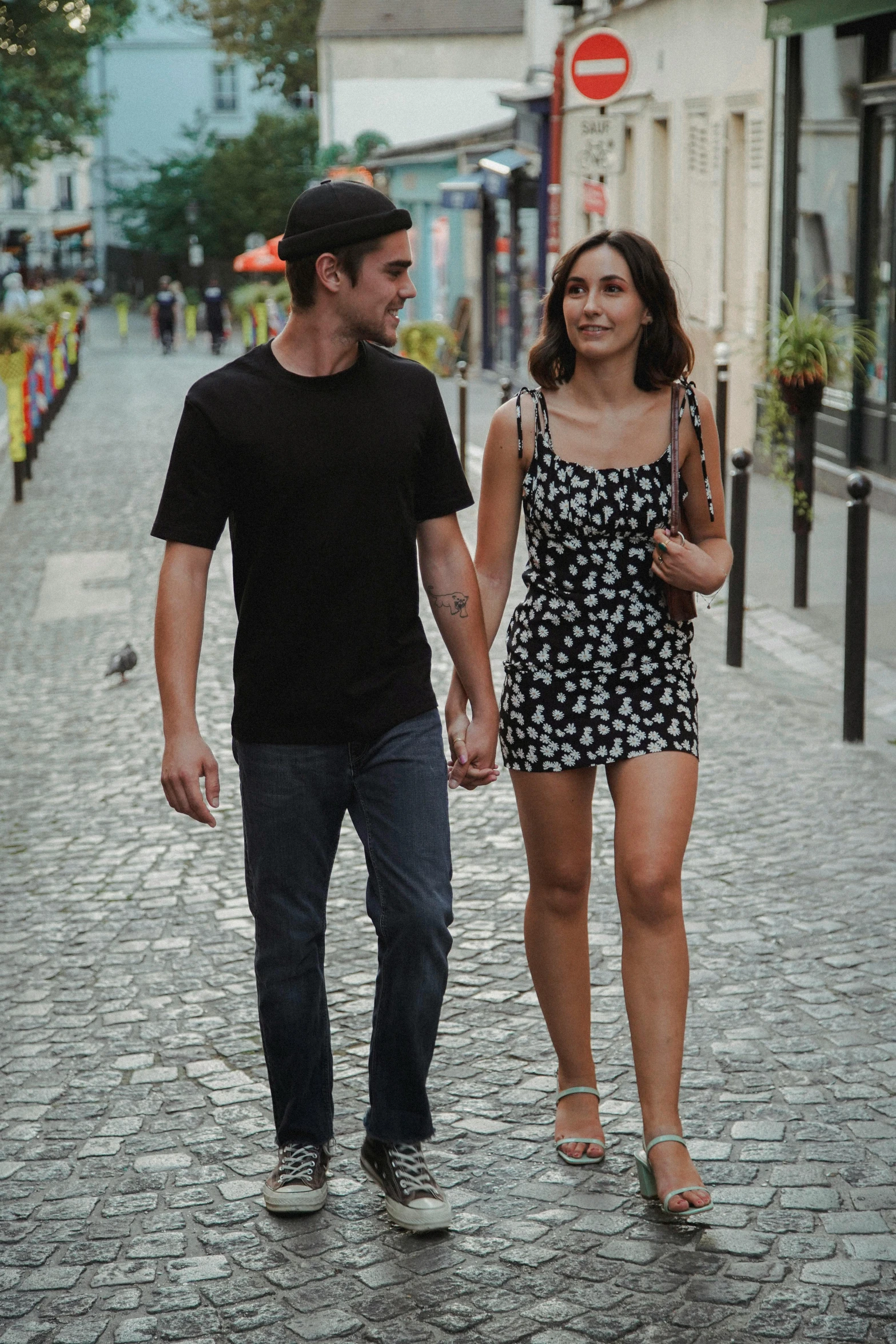 two people walking down the street on the cobblestone