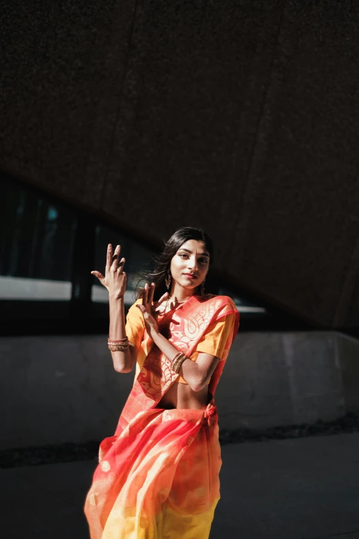 a lady dressed in a colorful indian sari holds her hands together