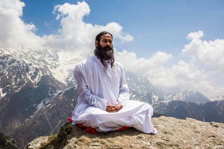 a person sitting in meditation position in the mountains