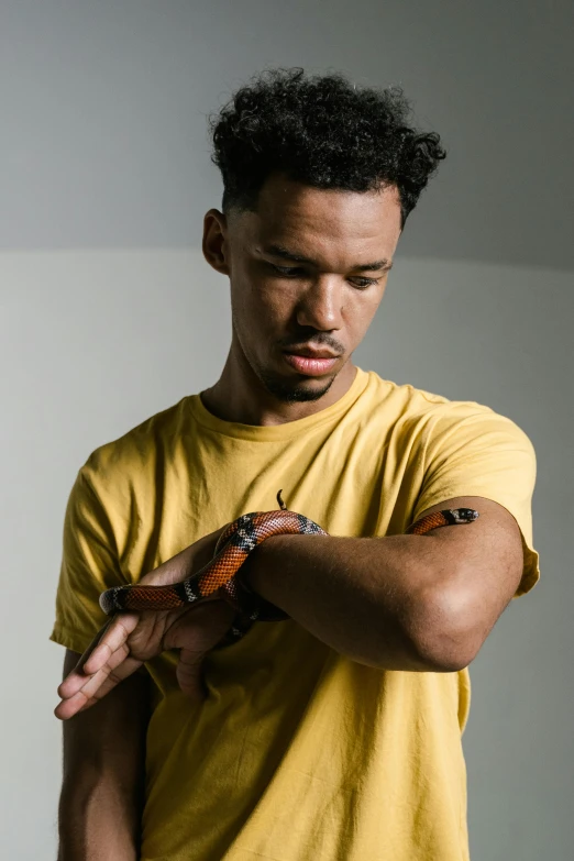 young man in yellow shirt holding out a snake to his hand