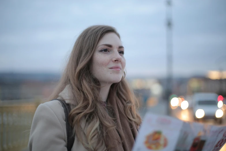 a lady with long brown hair and scarf holding a book