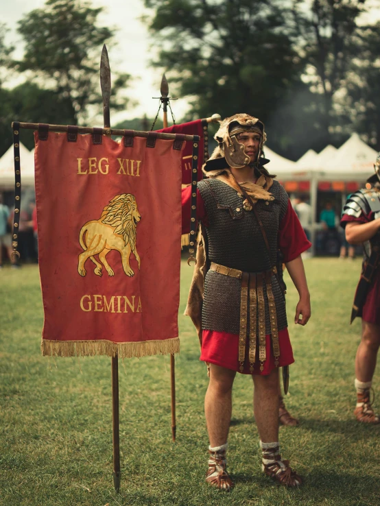 a man dressed in spartan clothing stands beside a sign