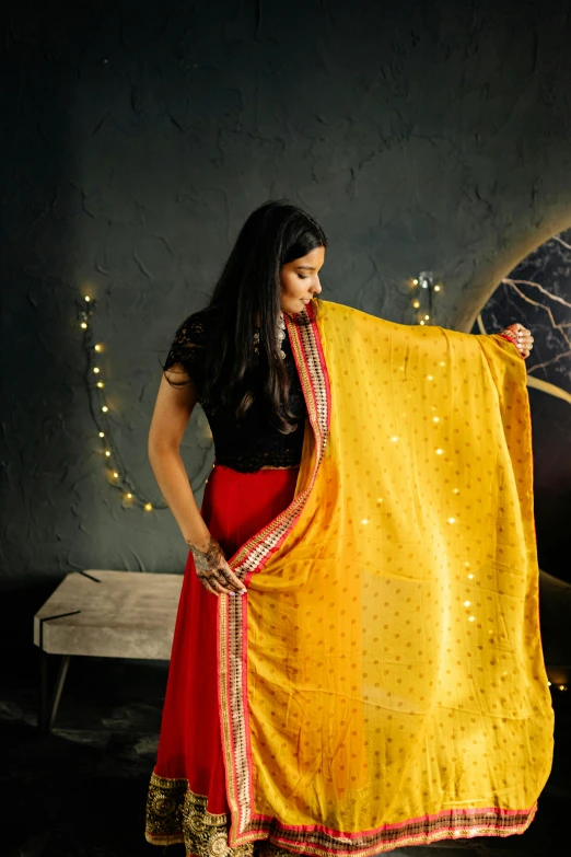 a woman in red and yellow dress holding up a yellow blanket