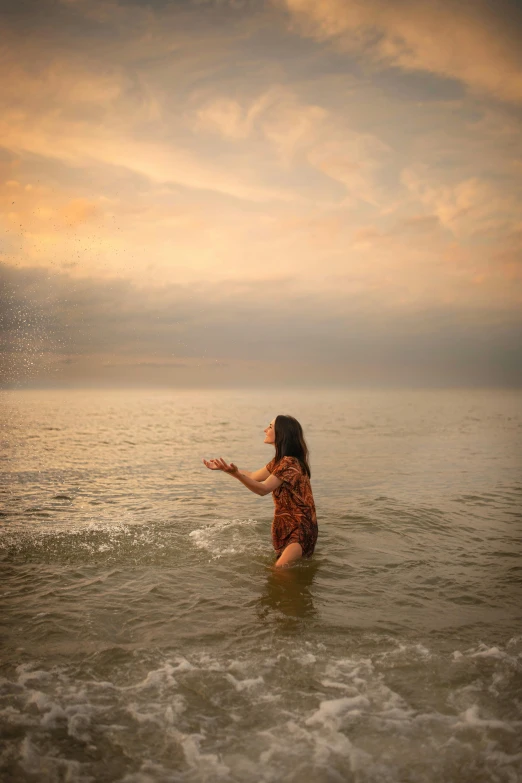 a girl is wading out in the water holding an umbrella