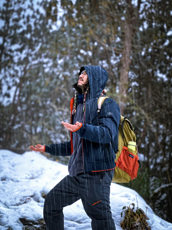 the man in the jacket is standing and is wearing a hooded coat