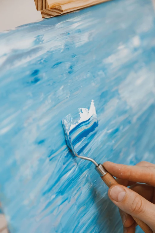 someone paints blue and white onto a piece of paper