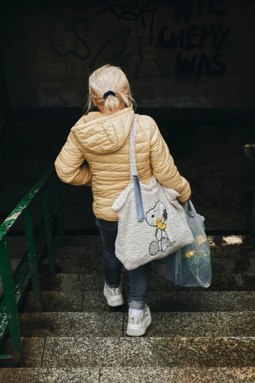 a woman carrying a bag walking up some stairs