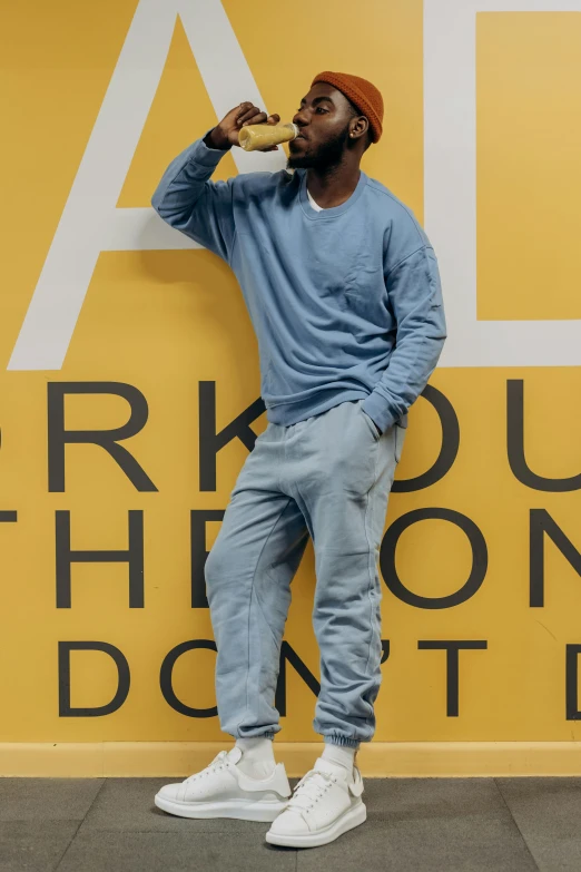 a man stands by a sign while eating a doughnut