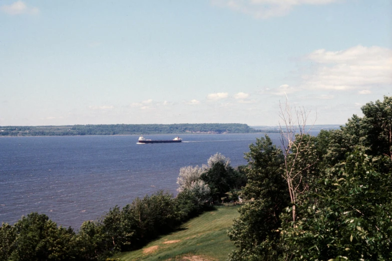 the view from a hill shows a boat traveling across the water