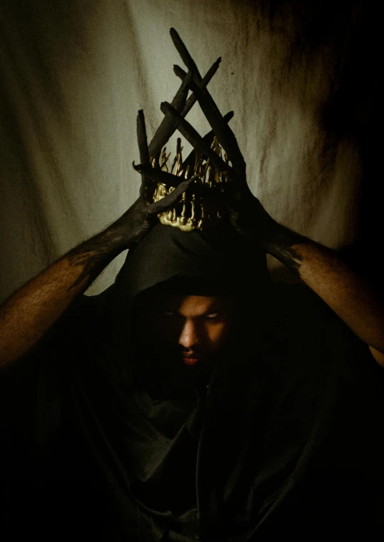 a man with dark clothing is holding a wooden cross