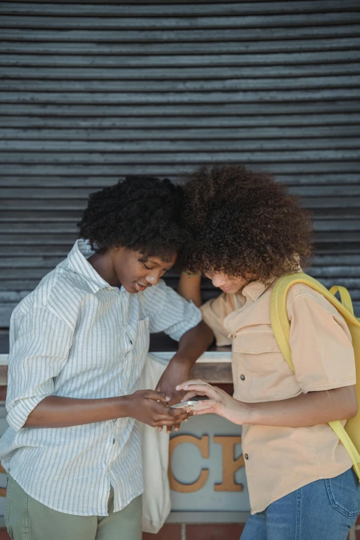 two people are looking at their phones while one holds her hand