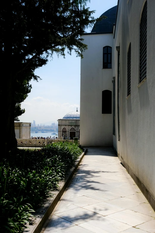 a sidewalk in front of a building with water in the background