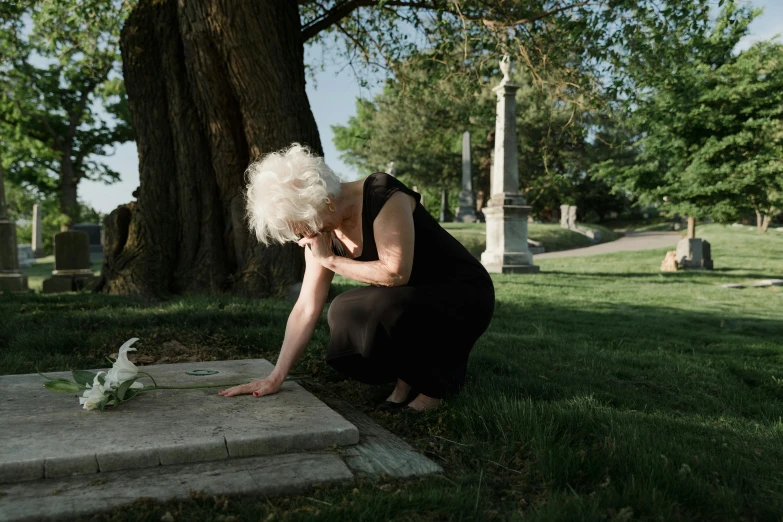 a woman bending down while kneeling over a stone block on a green field