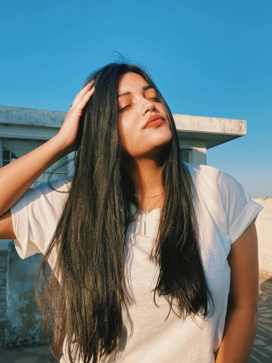 young woman standing outside while looking up at a blue sky