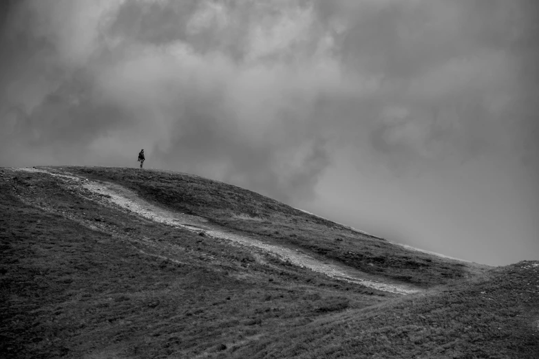 man standing on top of a mountain in black and white